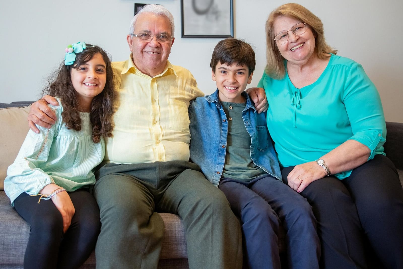 Abuelos y dos nietos sonriendo, sentados juntos en un sofá